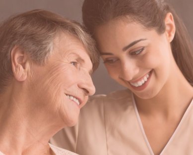 senior woman and caregiver smiling at each other