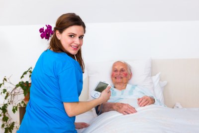 caregiver measuring senior woman's blood pressure