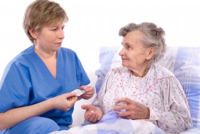 caregiver giving medicine to senior woman